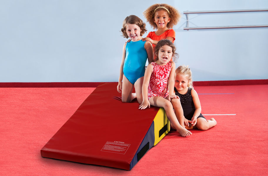 Beginner gymnasts with a wedge mat in a gymnastics studio